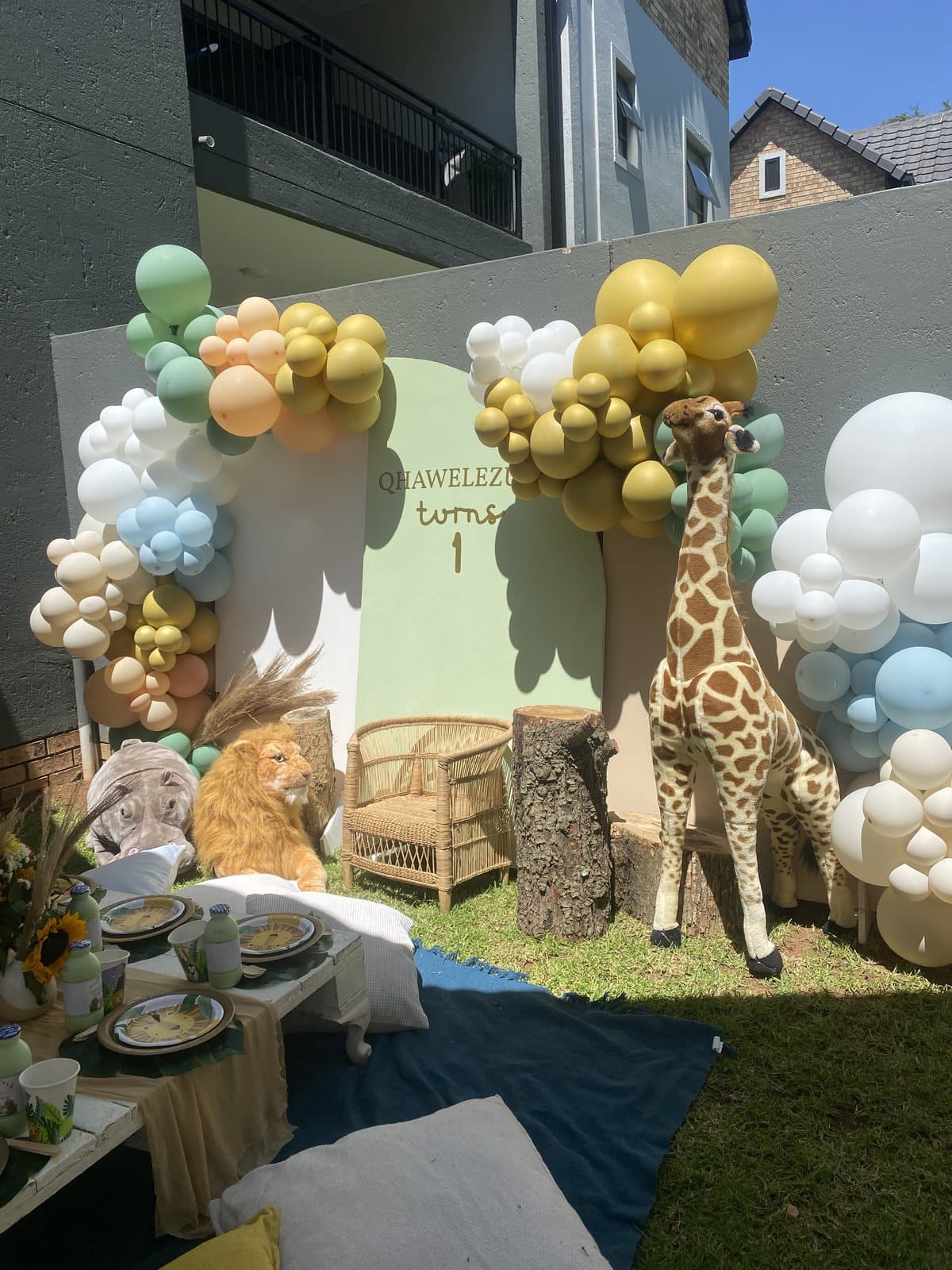 Pastel yellow and white balloon arch with a giraffe plush for a baby shower