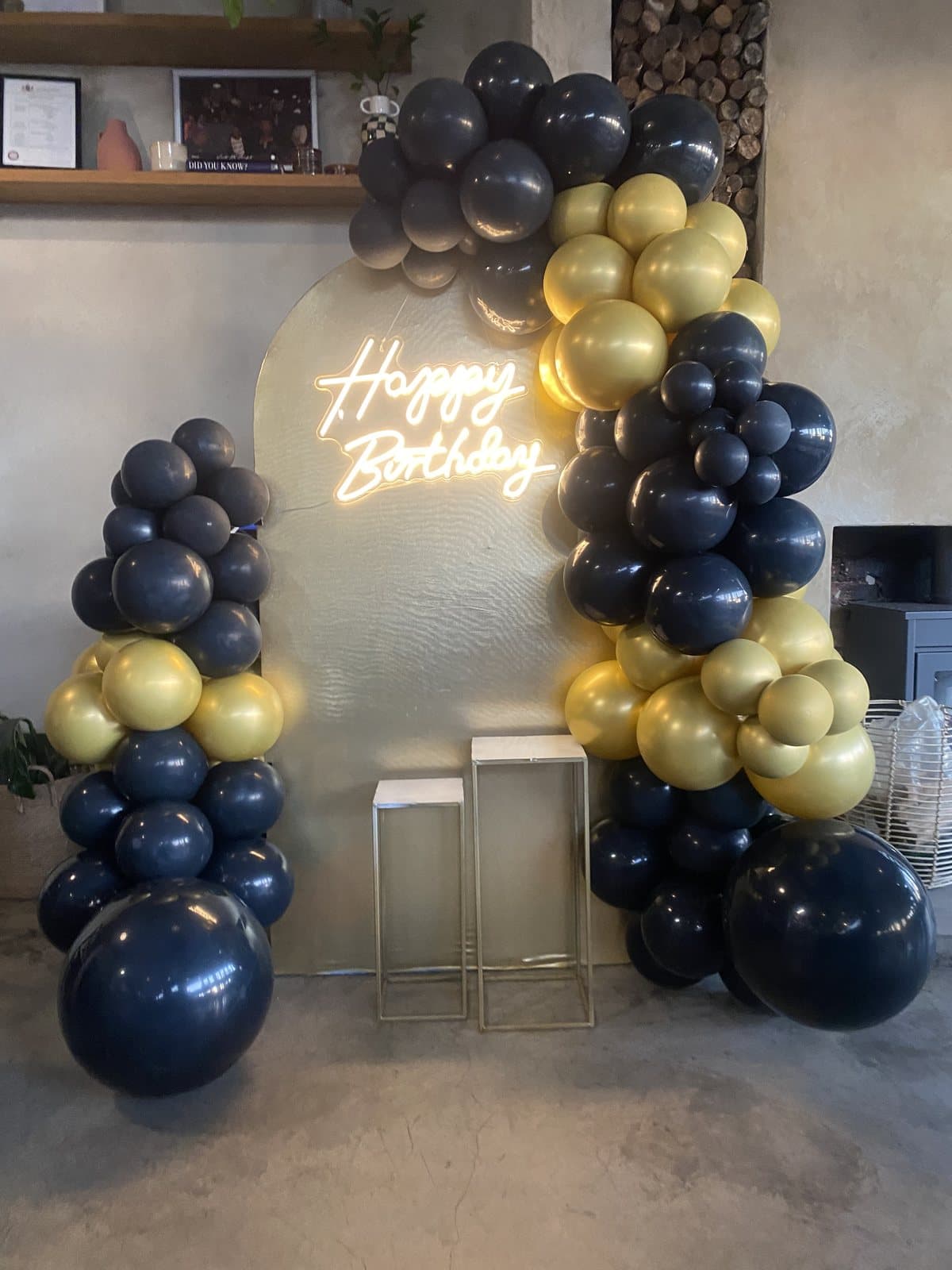 Black and gold balloon backdrop with a neon-style Happy Birthday sign