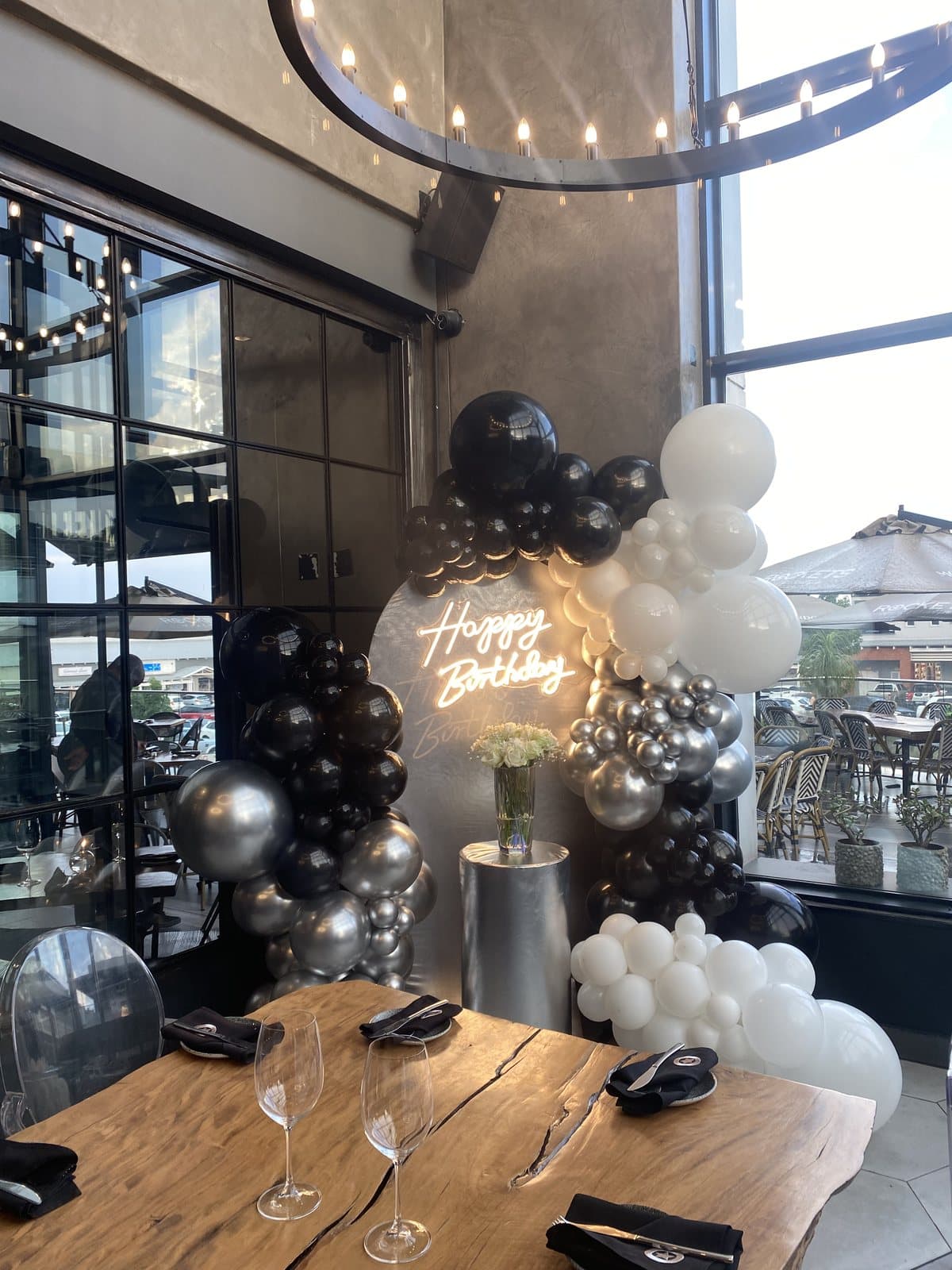 Black and white balloon column with string lights for an adult birthday celebration