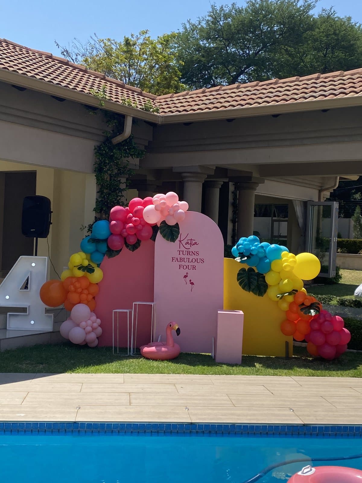 Poolside pink and red balloon arch for a birthday celebration