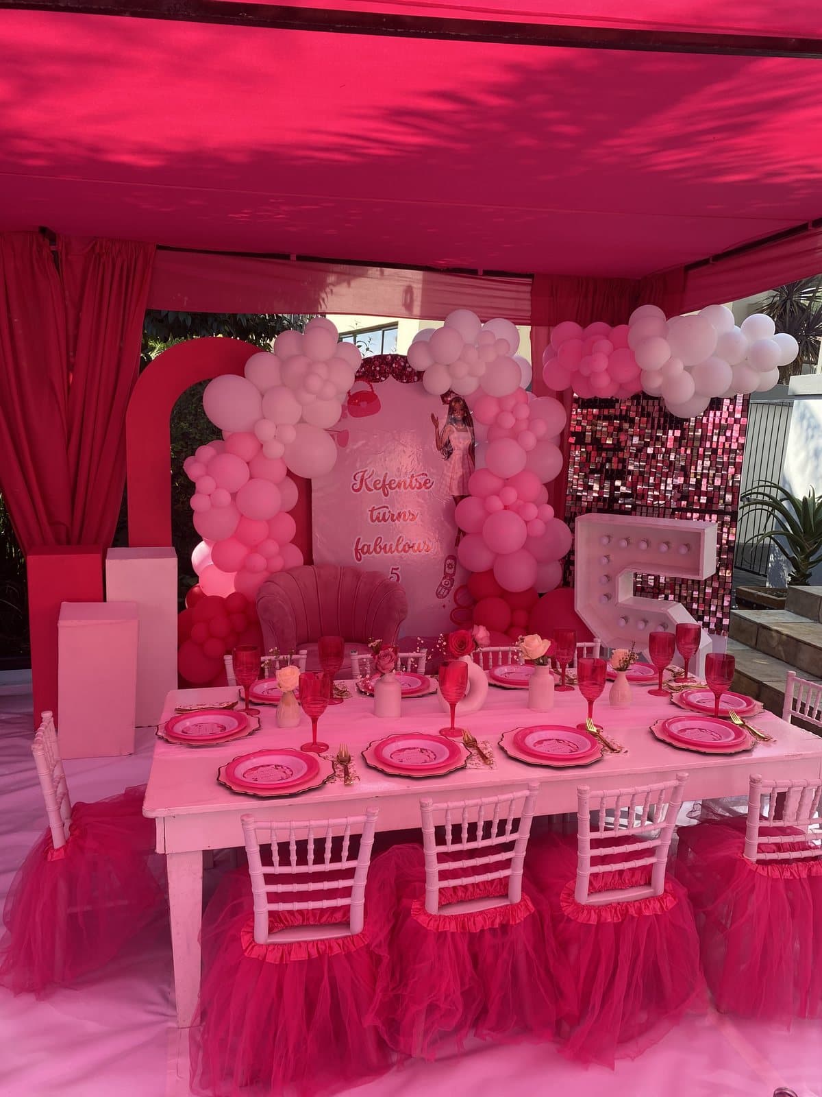 Hot pink tablescape inside a red-draped tent for a Barbie themed party
