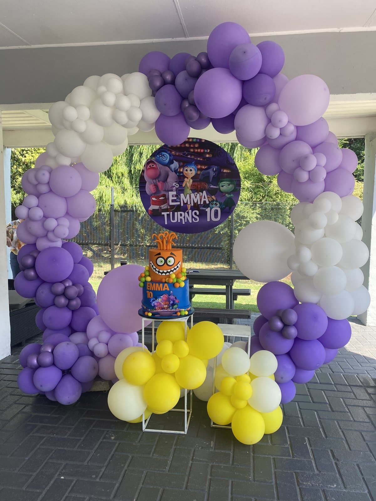 Purple, white and yellow Inside Out themed balloon arch and cake for a tenth birthday party