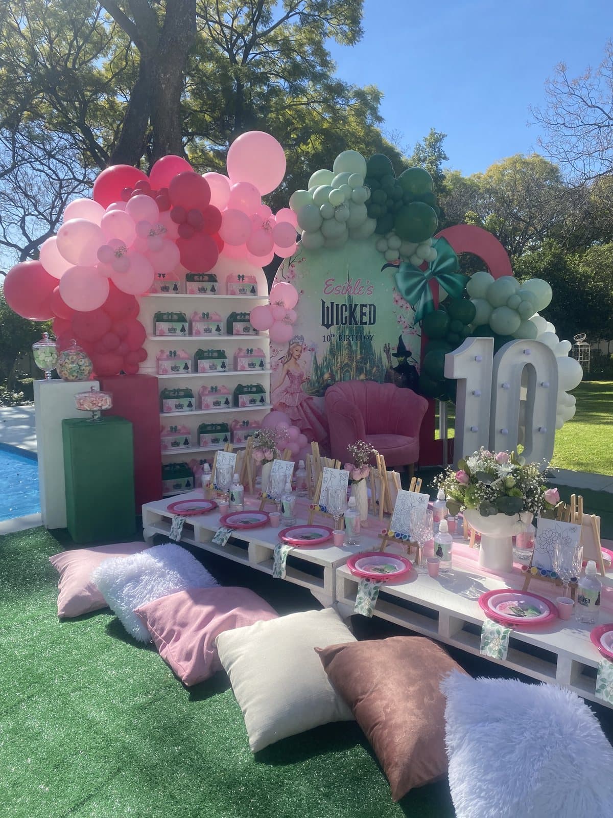 Green and pink balloon arch and styled picnic table for a tenth birthday