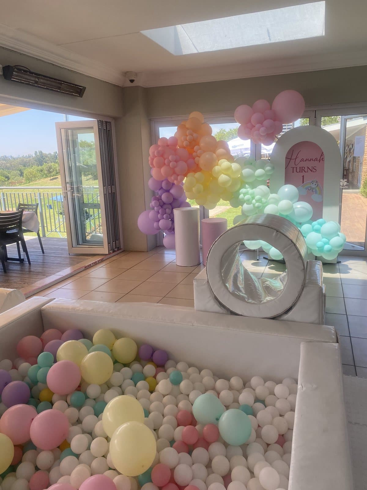 Pastel balloon-filled ball pit set up indoors for a kids party