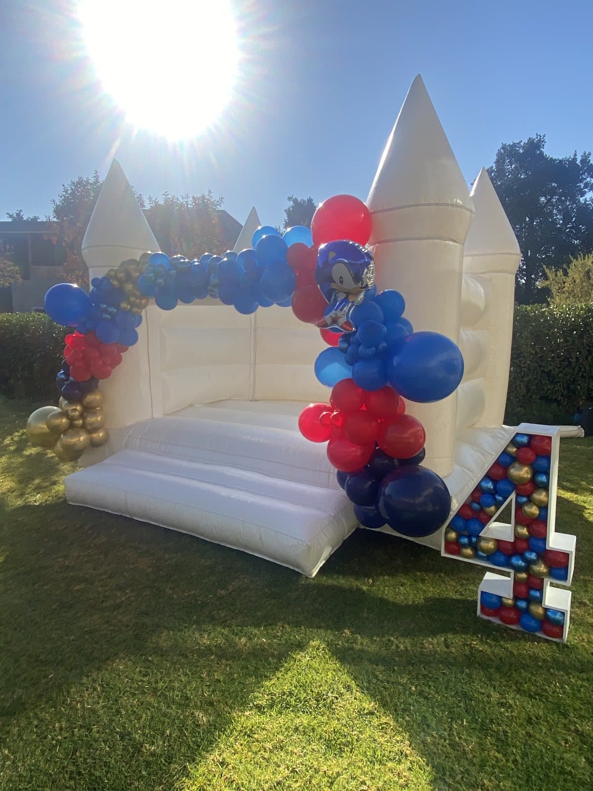 White castle bounce house with a red, blue and yellow LEGO-style balloon numeral four