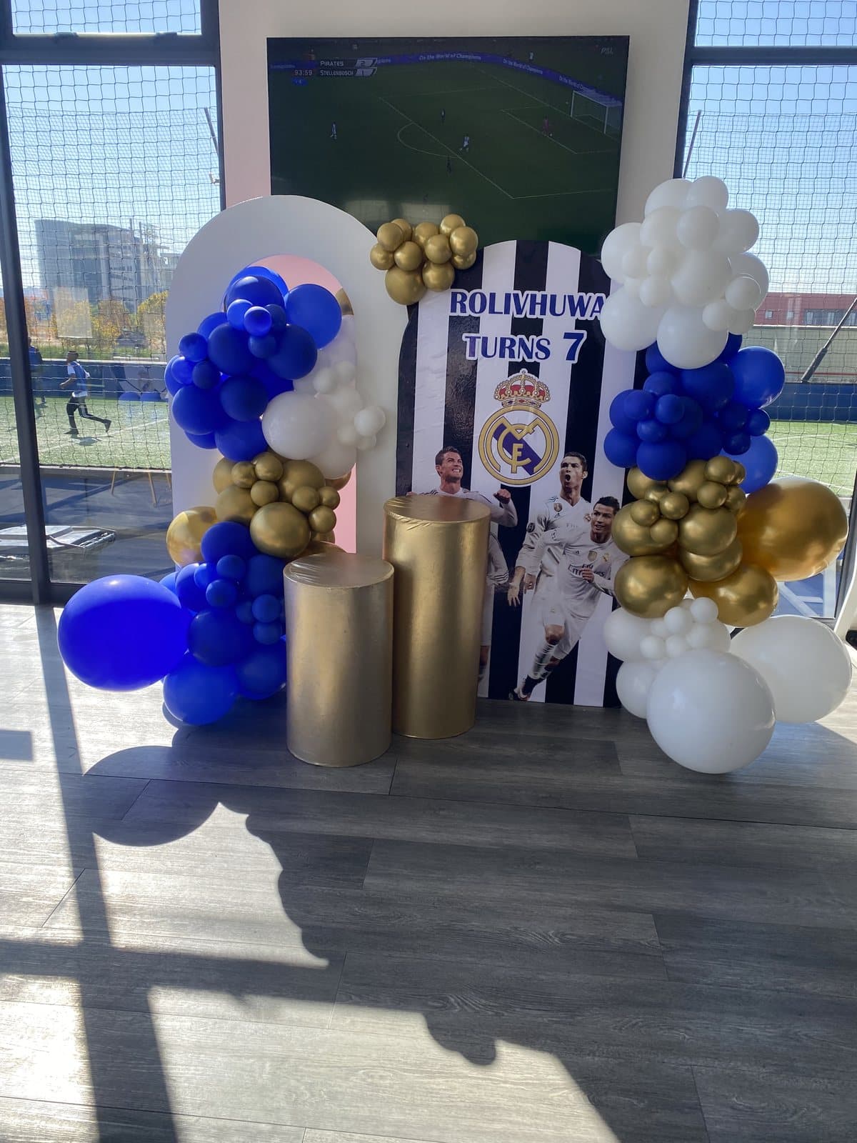 Navy and gold balloon arch with photo displays for an indoor birthday party