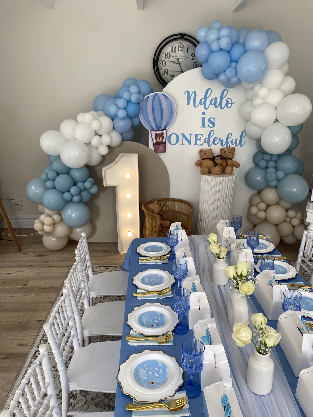 Blue and white balloon arch and table setting for a first birthday party