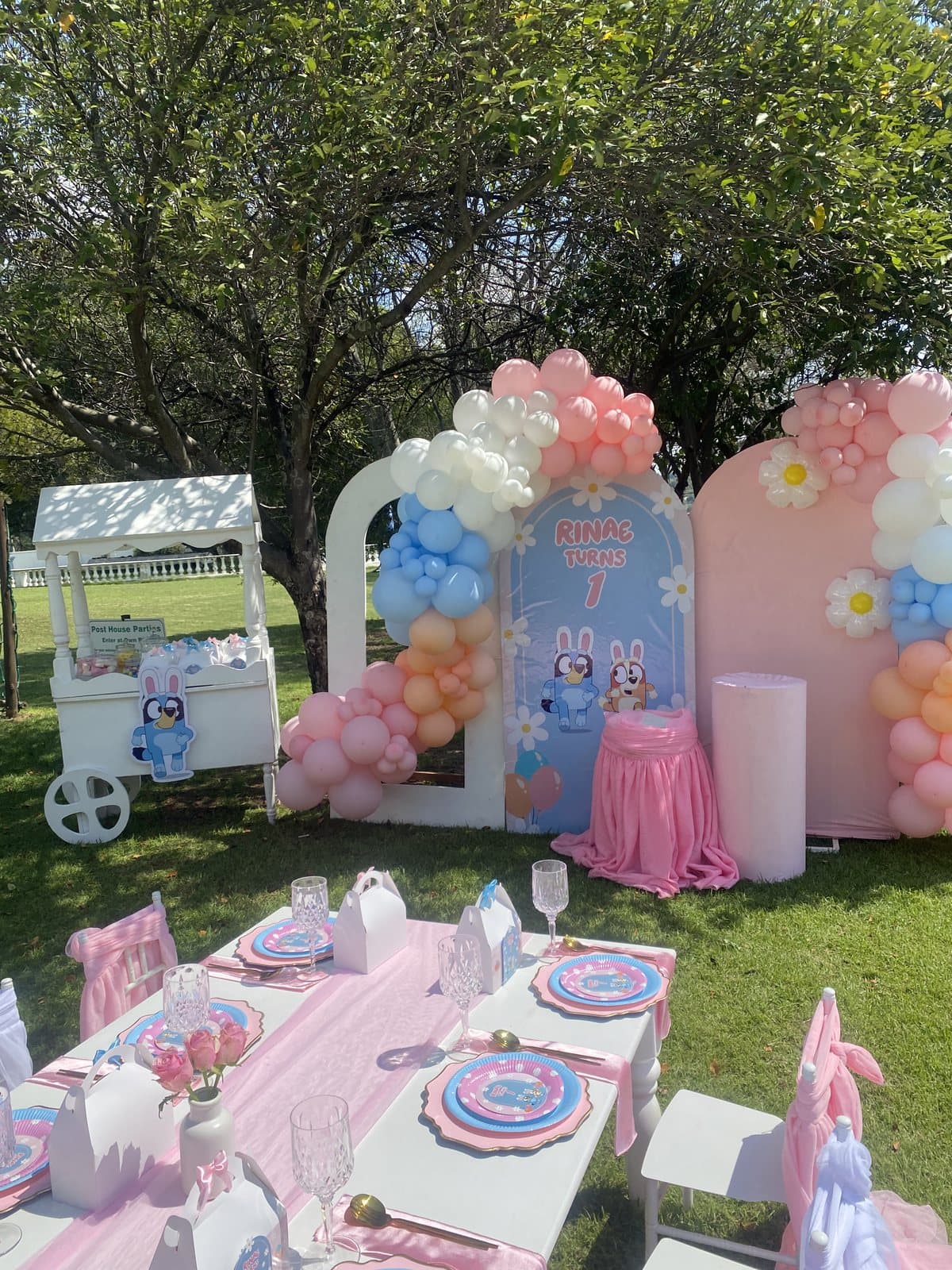 Pastel dessert cart styling with balloon columns and pink tablecloths