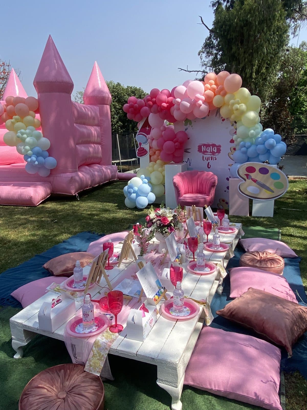 Pink princess castle bounce house with a styled pastel picnic table