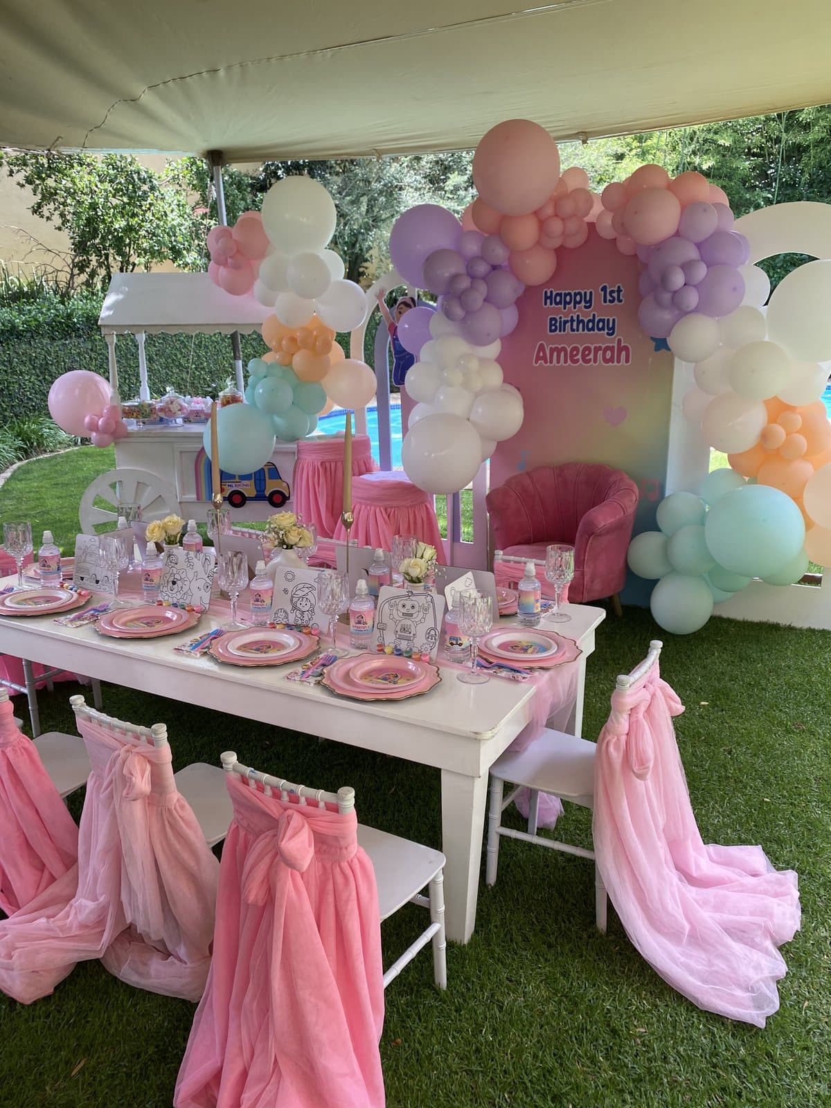 Pink pastel balloon arch with an elegant table setting for a first birthday party