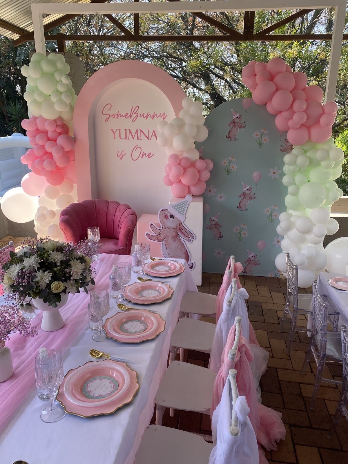 Elegant pink tablescape under a pergola for a first birthday celebration