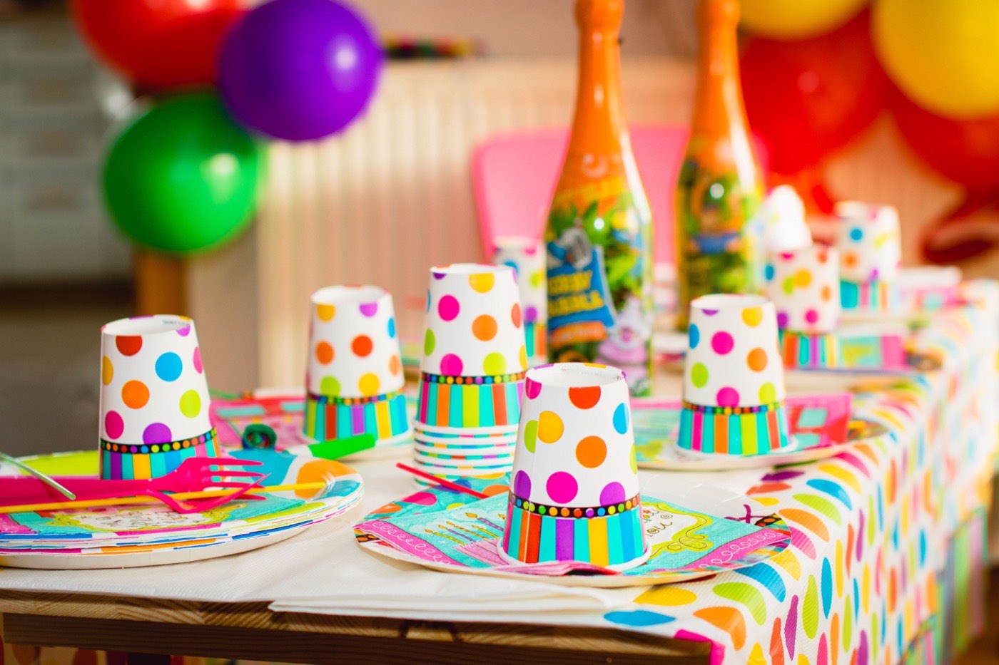 A colourful polka dot party table set with paper cups, plates and napkins