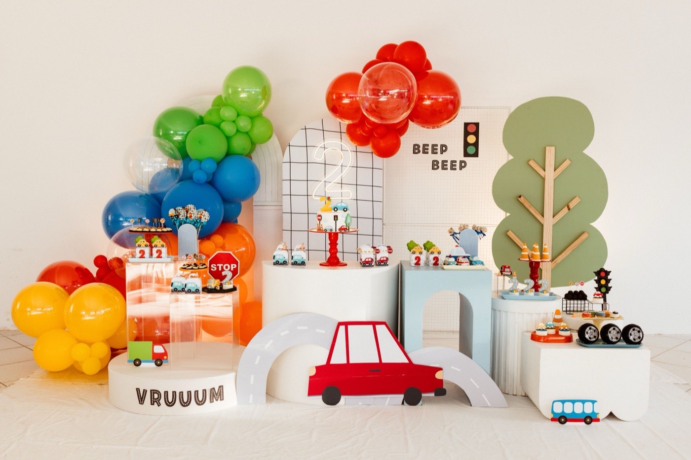 A car and road themed birthday dessert table with balloon garlands