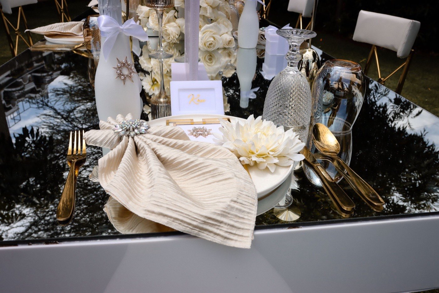 A place setting at an elegant wedding table with a named place card and fresh roses